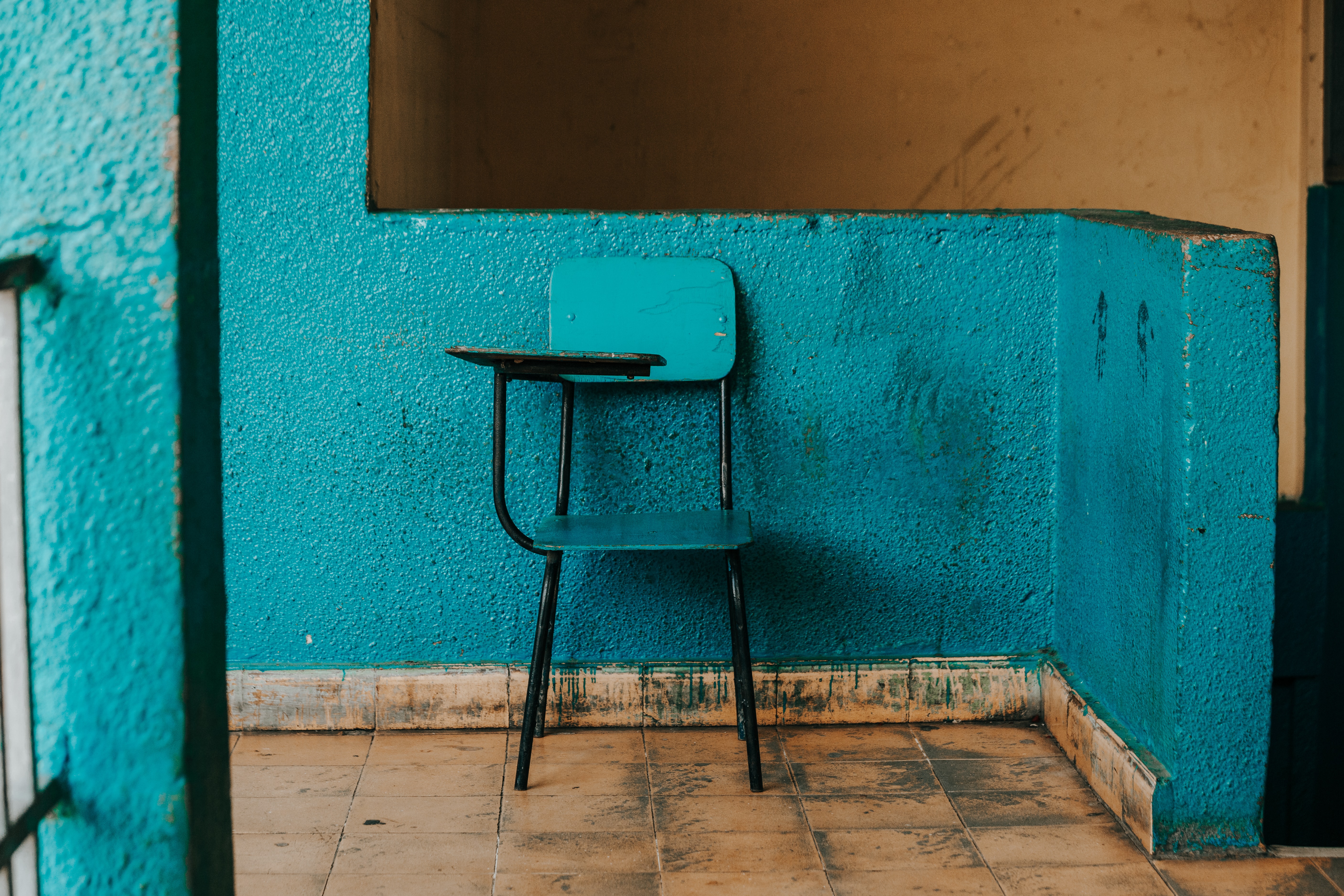 blauer Stuhl mit Tisch vor einer blauen Wand