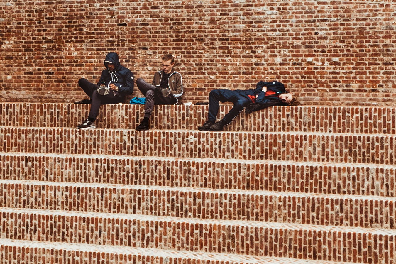Jugendliche sitzen auf einer Treppe und nutzen ihre Mobilgeräte