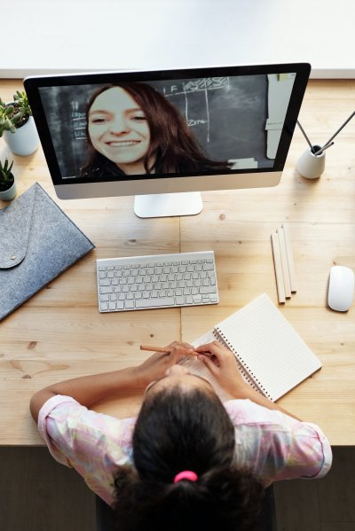 Mädchen aus Vogelperspektive vor Computer in einem Videogespräch mit junger Frau