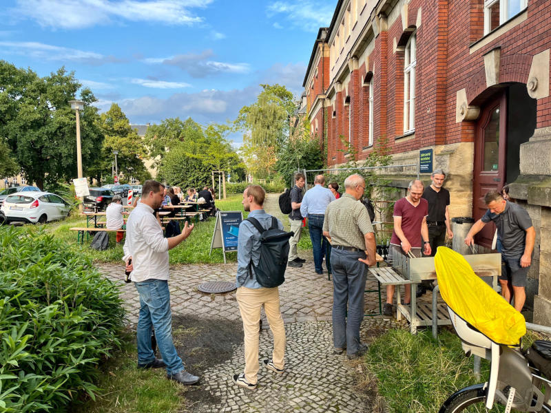 Mehrere Personen unterhalten sich beim abendlichen Grillen der Lessons Learned Conference 2024.