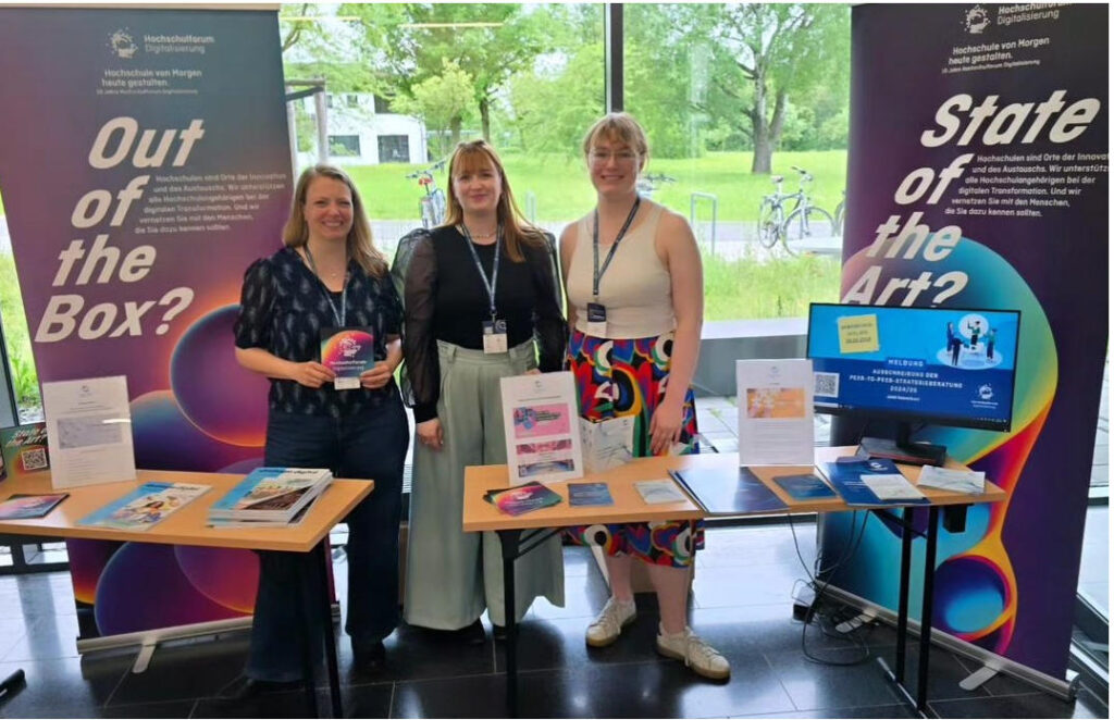 Drei Frauen stehen am HFD-Stand beim QUADIS-Symposium in Würzburg.