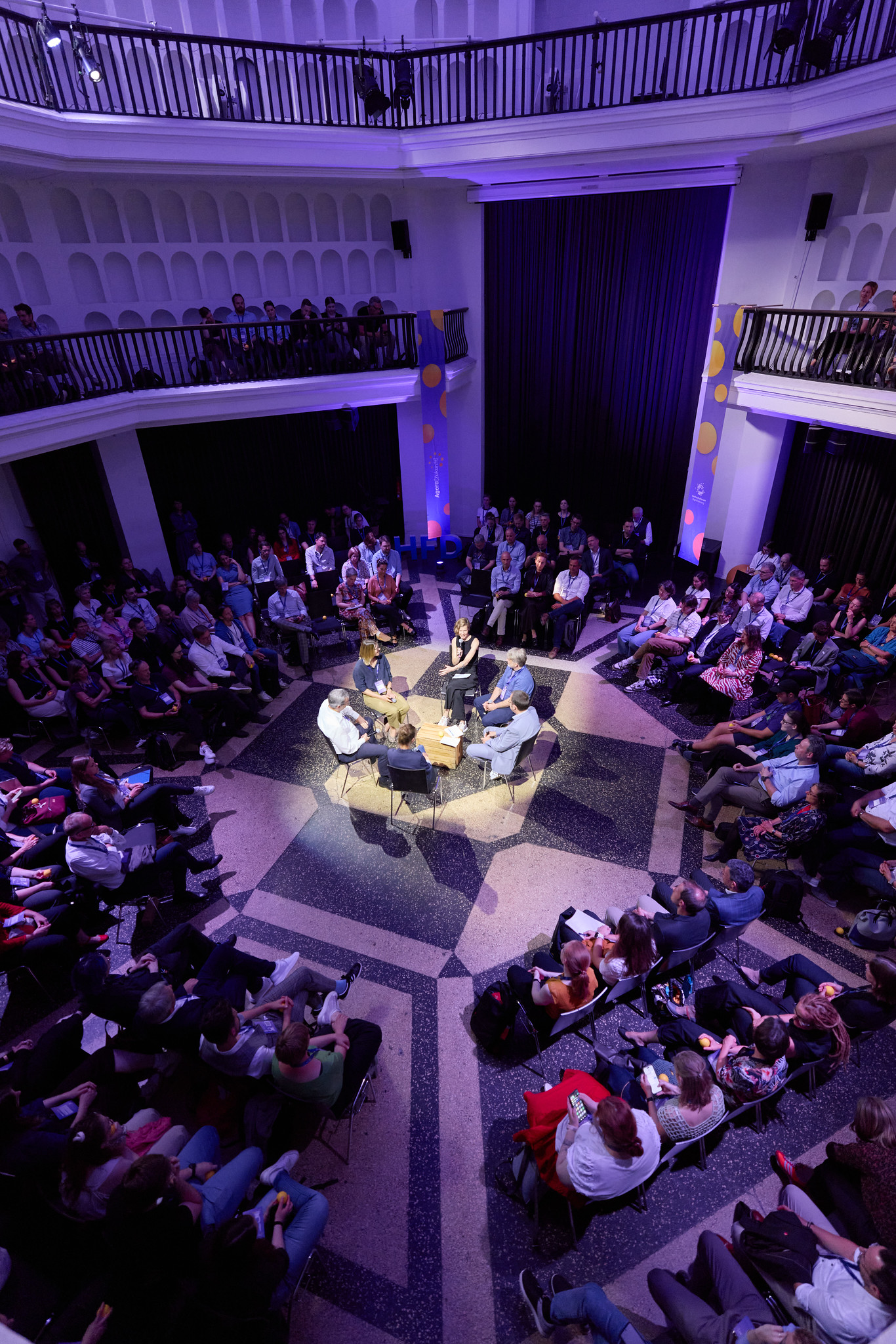 Fish-Bowl-Diskussion bei der letzten Agora Zukunft 2025. Im Zentrum sitzen die Moderatorin und fünf Diskussionsteilnehmende. Ringsherum das Publikum.